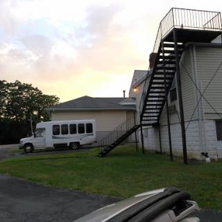 A view of a building with an external staircase and a parked vehicle nearby.