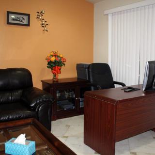 A cozy office space with a desk, chairs, and a leather sofa.
