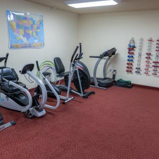 A small gym with exercise equipment including a treadmill and stationary bikes.