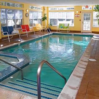 A cozy indoor swimming pool with seating and large windows letting in natural light.