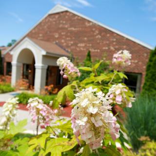 A brick building surrounded by a garden with blooming flowers.