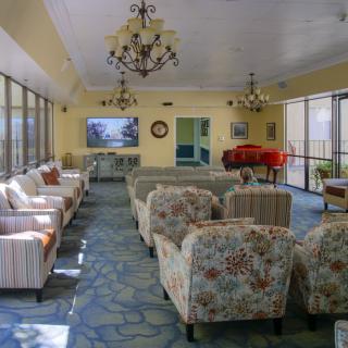 A spacious lounge area featuring comfortable seating, chandeliers, and a piano.