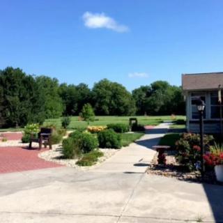 A scenic garden with paved paths and lush greenery under a clear blue sky.
