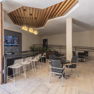 A modern cafe interior featuring sleek bar stools, stylish lighting, and a unique ceiling design.