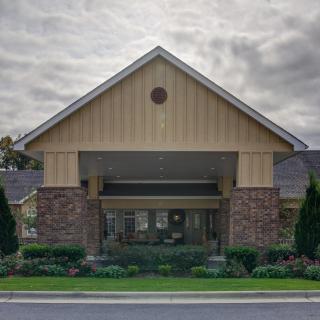 A front view of a building entrance with landscaping under a cloudy sky.