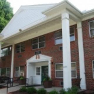 A two-story brick apartment building with large white columns at the entrance.