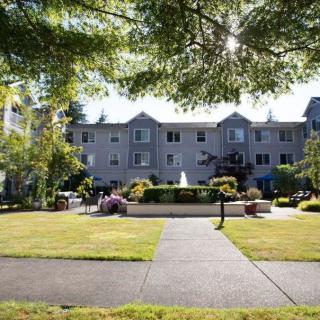 A picturesque view of a residential building surrounded by a well-kept garden and pathway.