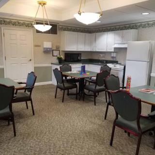 A communal kitchen area with multiple tables and chairs, equipped with appliances such as a refrigerator and microwave.