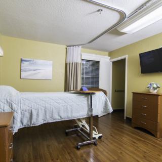 A clean and organized hospital room with a bed, television, and essential furniture.