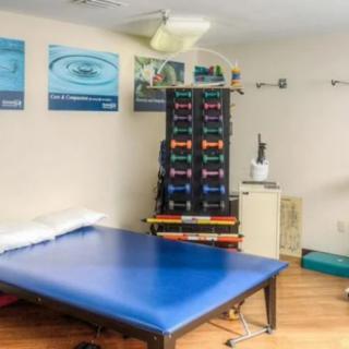 A rehabilitation room equipped for physical therapy with a treatment table, exercise equipment, and medicine balls.