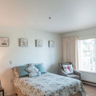 A cozy bedroom with a bed, decorative pillows, and a chair by the window.