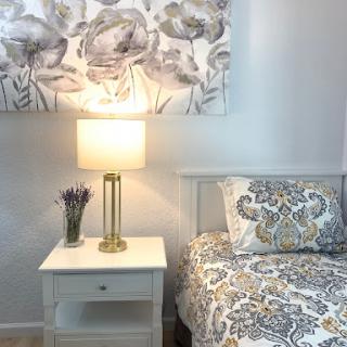 A cozy and well-decorated bedroom featuring a stylish nightstand, decorative lamp, and patterned bedding.