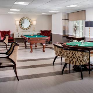 A stylish game room featuring a pool table, poker table, and comfortable seating.