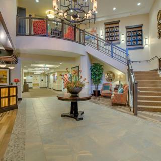 Spacious hotel lobby with a grand chandelier and elegant staircase.