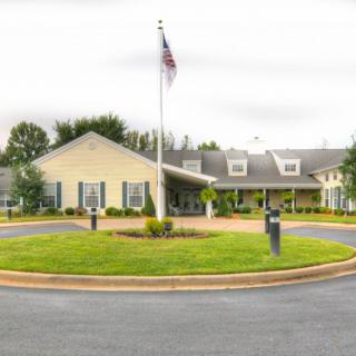 A symmetrical building with a flagpole and circular driveway in front.