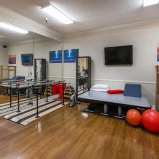 A well-equipped physical therapy room featuring parallel bars, a treatment table, and exercise balls.