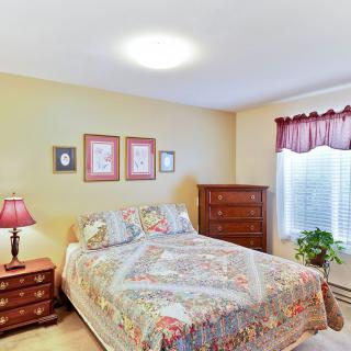 A cozy bedroom with a neatly made bed, dresser, and decorative artwork on the walls.
