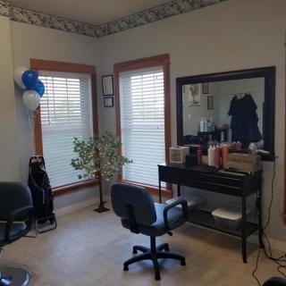 A cozy hair salon interior with chairs and a large mirror.