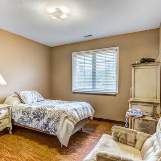 A cozy bedroom with a single bed, lamp, and comfortable chair.