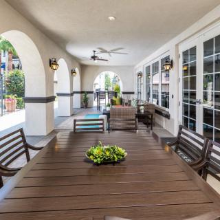 Spacious patio area with a large dining table and chairs, featuring arches and ceiling fans.