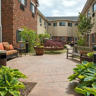 A peaceful courtyard with benches, plants, and a paved walkway between residential buildings.