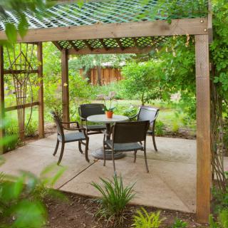 A cozy garden pergola with outdoor seating surrounded by lush greenery.