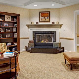 A cozy living room featuring a central fireplace, surrounded by bookshelves and comfortable seating.