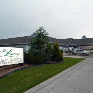 A roadside view of a building with a sign and a parked car.