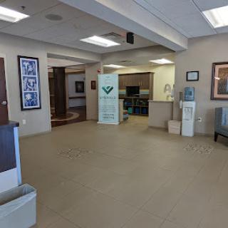 A spacious and welcoming reception area featuring comfortable seating, a water cooler, and decorative art.