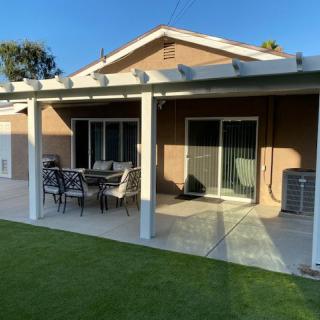 A backyard patio with outdoor furniture and a neatly maintained lawn.