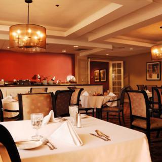 An elegant restaurant dining room with neatly set tables and warm lighting.