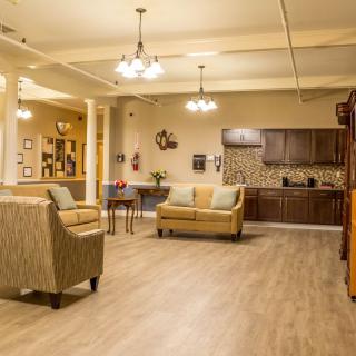 A cozy living room with a connected kitchen area, featuring comfortable seating and ambient lighting.