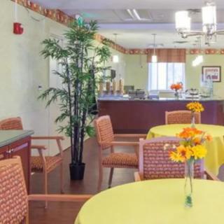 A cozy dining area with tables set for guests, featuring vibrant floral decorations and warm lighting.