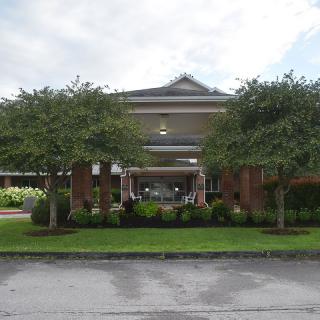 Front view of a building with a well-maintained garden and trees.