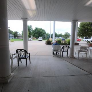 View from a covered patio area facing the parking lot with chairs and columns.