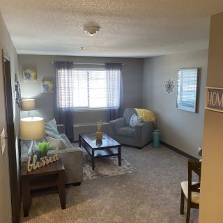 A cozy living room with a sofa, coffee table, and ample natural light.