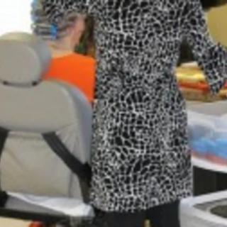 A person standing in an office wearing a patterned dress.