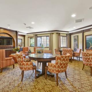 A well-furnished dining area with patterned chairs and round tables, featuring large windows and elegant decor.