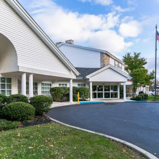 The exterior of a modern hotel with a driveway and well-maintained landscaping.