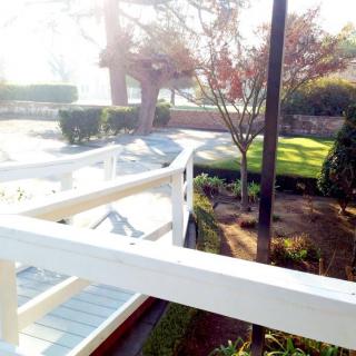 A serene garden view with a white bridge and trees bathed in sunlight.