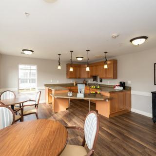 A modern kitchen and dining area featuring pendant lighting and wood flooring.