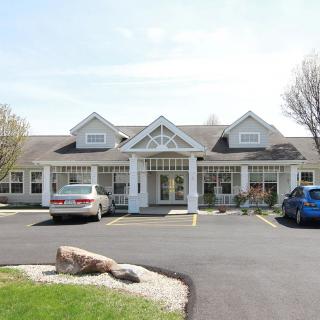 A suburban residential building with a parking lot and cars in front.