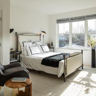 A modern, minimalist bedroom with ample natural light and stylish furnishings.