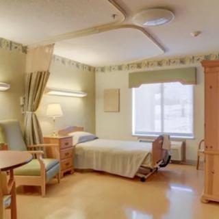 A well-lit hospital room with a single bed and seating area, designed for patient care.