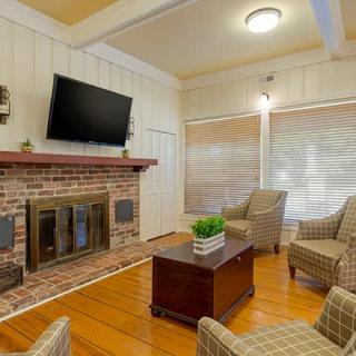 A cozy living room with a brick fireplace, television, and comfortable seating.