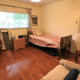 A cozy bedroom with a single bed, wooden flooring, and a window with curtains.