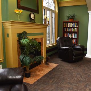 Cozy living room with green walls, a fireplace, and leather chairs.