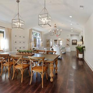 A modern and spacious dining room with elegant chandeliers and wooden flooring.