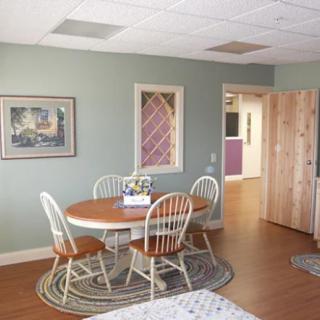 A cozy dining area with a round table and chairs, set on a wooden floor with a decorative rug.