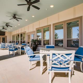 An inviting outdoor patio area featuring comfortable seating and ceiling fans.